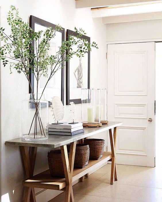 a table with two vases and some plants on it in front of a door