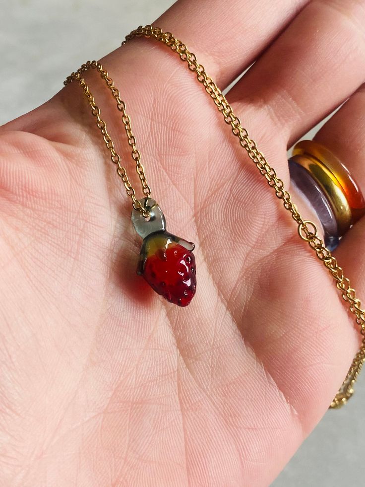 Strawberry glass charm with 14k gold plated chain. Not including the loop, the pendant is about 2.6 cm (1 inches) long and 1 cm (0.4 inches) wide. All the pendants and charms are created by melting borosilicate glass rods using a torch and annealed in a digitally controlled kiln for long-lasting durability. Due to the unique nature of this jewelry, each necklace will be slightly different. Everyday Gold Glass Jewelry, Everyday Nickel-free Resin Jewelry, Nickel Free Glass Pendant Jewelry, Everyday Gold Resin Jewelry, Everyday Glass Jewelry With Adjustable Chain, Small Brass Jewelry Gift, Unique Brass Charm Necklace For Gifts, Unique Brass Charm Necklaces As Gifts, Unique Brass Charm Necklaces For Gifts