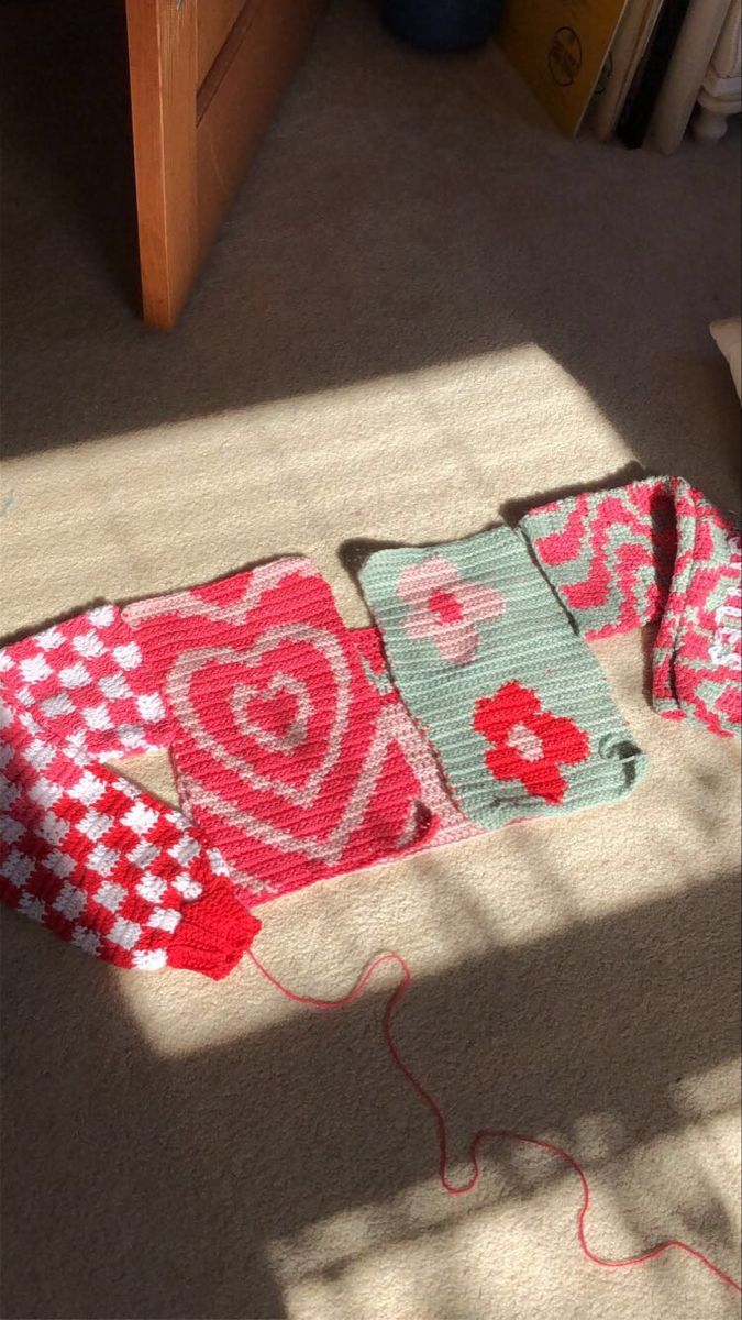 a crocheted blanket laying on the floor next to a table