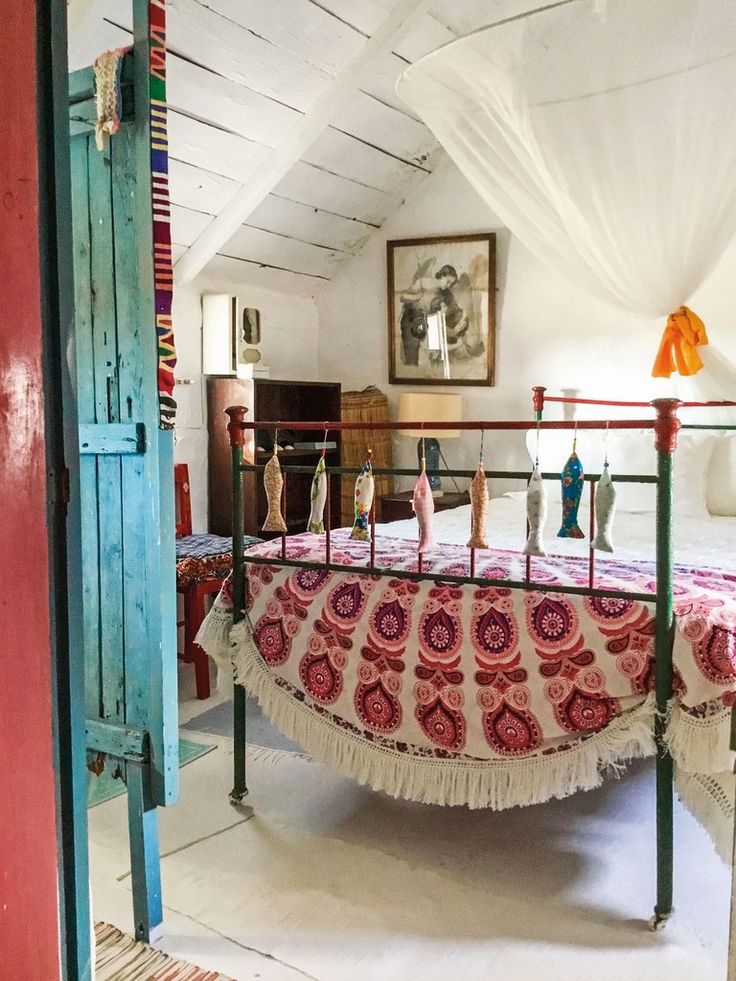 an old fashioned bed with colorful bedspread in a room that is painted white