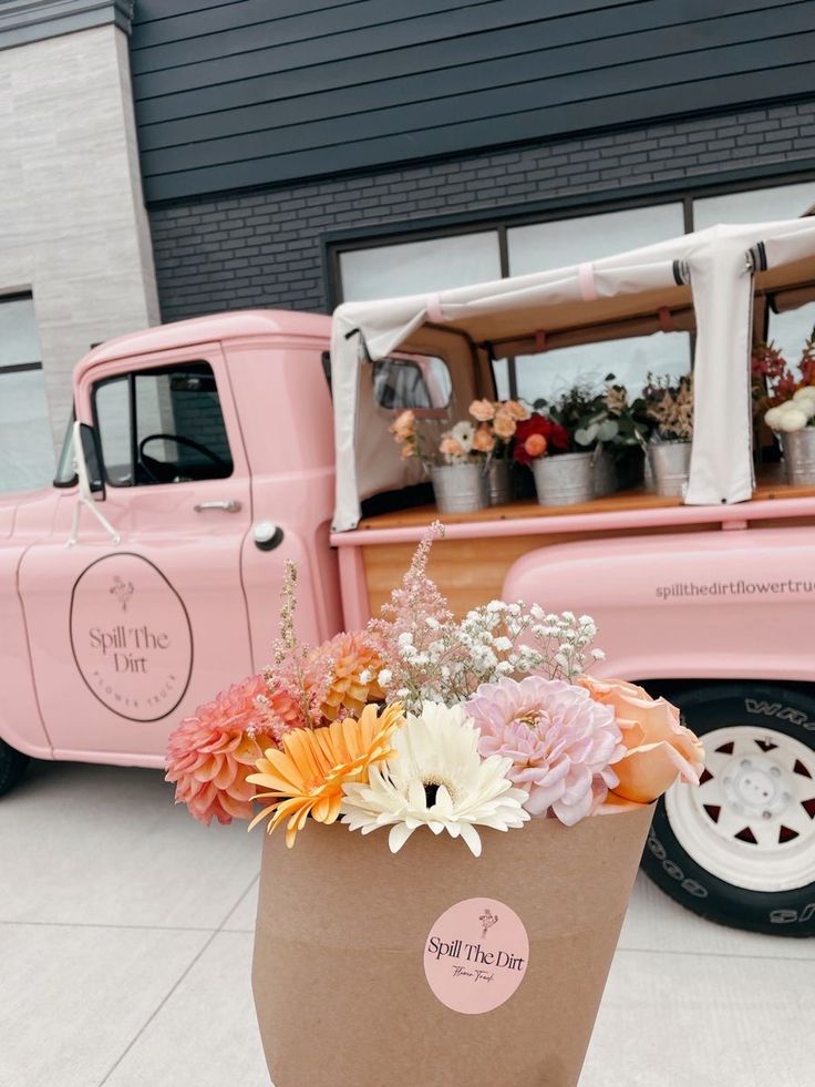 a pink truck parked next to a flower shop