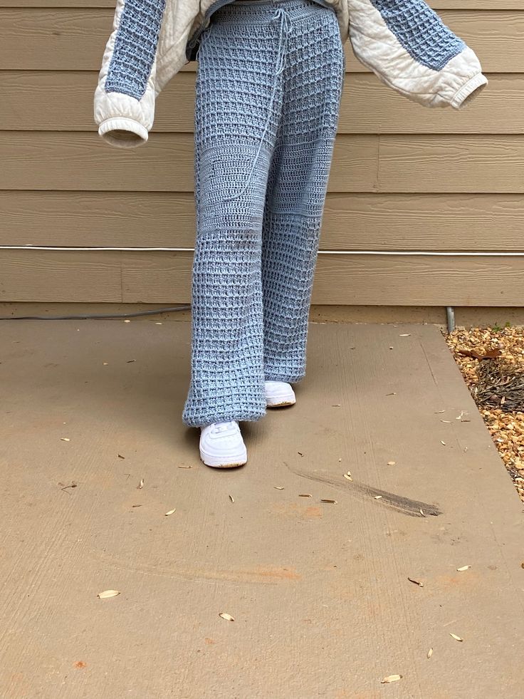 a woman in blue and white pants standing on a porch with her hands behind her back