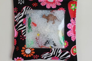 a black and pink frame with zebras, flowers and other things in it on a white surface