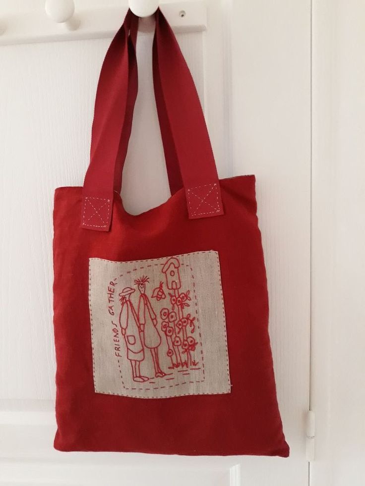 a red tote bag hanging on a white door with an image of a man and woman