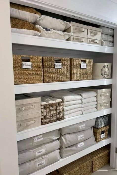 an organized closet with baskets and linens