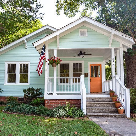 a small blue house with an american flag on the front door and steps leading up to it