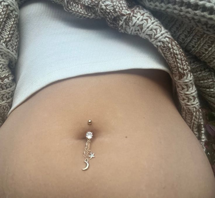 Channel your inner moon goddess with this beautiful gold moon belly ring ✨🌙 Made with clear quartz, gold chain, a star and moon charm. Belly ring base is 14g surgical steel with a cubic zirconia center. 🤍   Total drop length is 2-2.5 inches. >> BUY 3 GET 1 FREE <<  *no coupon code needed. when you purchase 3 belly rings from my shop you'll automatically receive a 4th one for free  SILVER MOON BELLY RING:  https://www.etsy.com/listing/1560417581/crystal-moon-dangle-belly-rings-hippie?click_key=1794e91fbd7cdefab3bef88cc1f7c79c5a7bd158%3A1560417581&click_sum=d3e2de51&ref=shop_home_active_4&frs=1&sca=1 CUSTOM BELLY RINGS:  https://www.etsy.com/listing/1436127690/crystal-belly-rings-hippie-belly-button?click_key=b0ba7087a3dd44ac30071855bf58f0b0fce4445c%3A1436127690&click_sum=3886f4aa&ref=shop Rings Moon, Rings Hippie, Belly Button Rings Dangle, Belly Button Jewelry, Dangle Belly Rings, Crystal Moon, Belly Jewelry, Belly Bars, Belly Button Ring