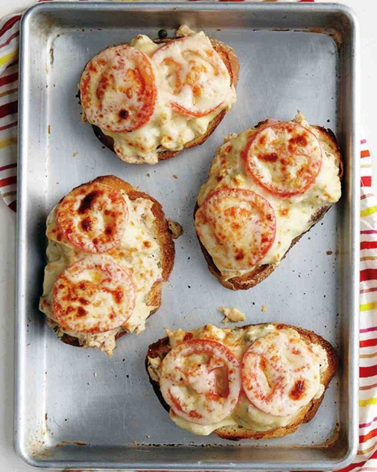 four pieces of bread with cheese and tomatoes on them