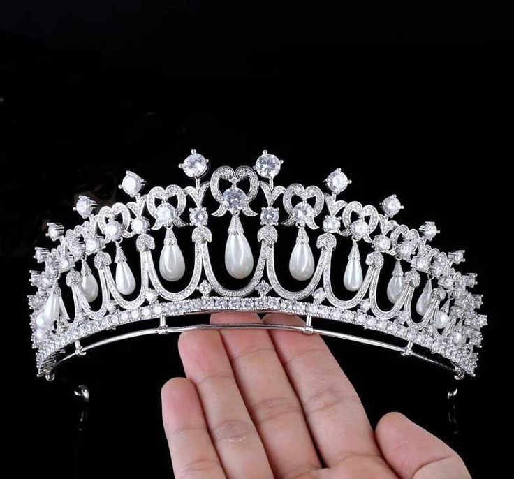 a hand holding a tiara with pearls and diamonds