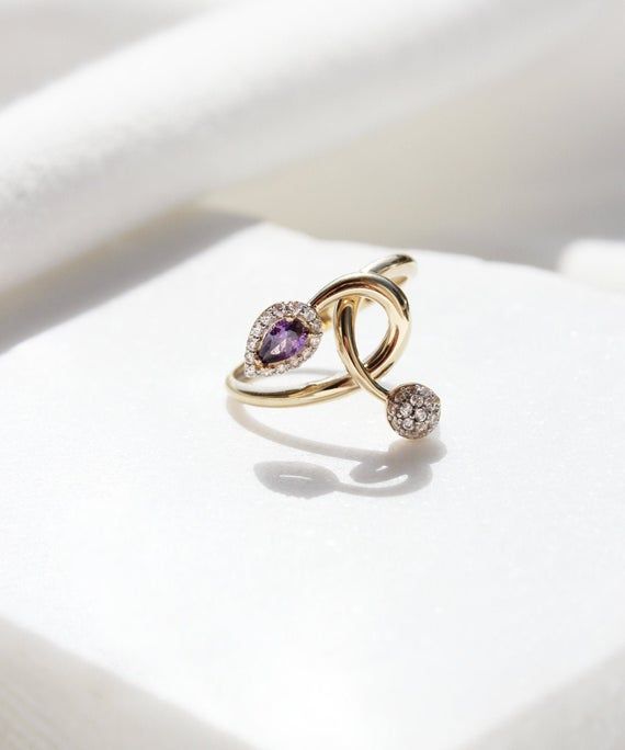 A beautiful and romantic 14K gold ring featuring a teardrop purple cubic zirconia stone and a little globe. This ring has a unique design and is one of a kind. We wont be making a second one of this ring, so if you love it hurry up! #february #birthstone #purple #ring #gold #aesthetic #minimalist #bridal #jewelry #unique Luxury Rose Gold Infinity Jewelry, Luxury Infinity Jewelry With Cubic Zirconia, Luxury Cubic Zirconia Infinity Jewelry, Luxury Infinity-shaped Cubic Zirconia Jewelry, Elegant Infinity Gemstone Jewelry, White Gold Infinity Fine Jewelry, Fine Jewelry Infinity Shape For Formal Occasions, Infinity Halo Jewelry Gift, Fine Jewelry With Infinity Gemstone