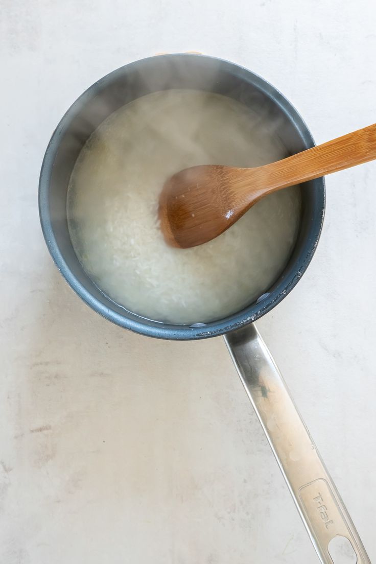 a wooden spoon in a pan filled with milk and water on a white counter top