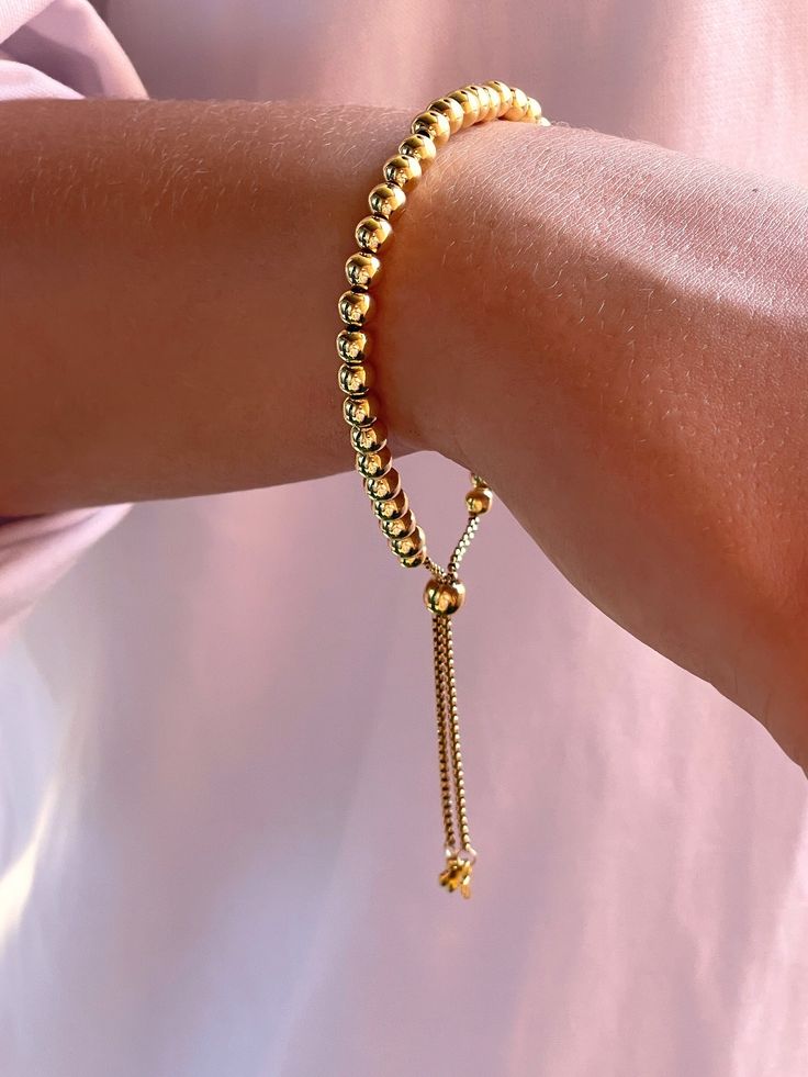 "\"Crafted from brass, these beaded bracelets exude a golden glow that's both timeless and elegant. Each bead measures approximately 0.18 inches (4.5 mm), ensuring a delicate and refined appearance. With an adjustable inner diameter ranging from 2 to 3-1/8 inches (5.2 to 7.9 cm), it promises a comfortable fit for various wrist sizes. Embrace the blend of simplicity and sophistication in this stunning piece.\" Care and Storage Recommendations: To prolong the life of your jewelry, avoid contact wi 14k Gold-filled Yellow Gold Jubilee Beaded Bracelets, Adjustable Gold Plated Beaded Bracelets With Round Beads, Dainty Adjustable Gold Beaded Bracelets, Adjustable Gold-plated Bracelets, Adjustable Gold-plated Bracelets With Round Beads, Beaded 14k Gold Filled Yellow Gold Bracelets, Adjustable 14k Gold-filled Bracelet With Beads, Adjustable Gold Dainty Rosary Bracelet, Everyday Yellow Gold Bracelet With 8mm Beads