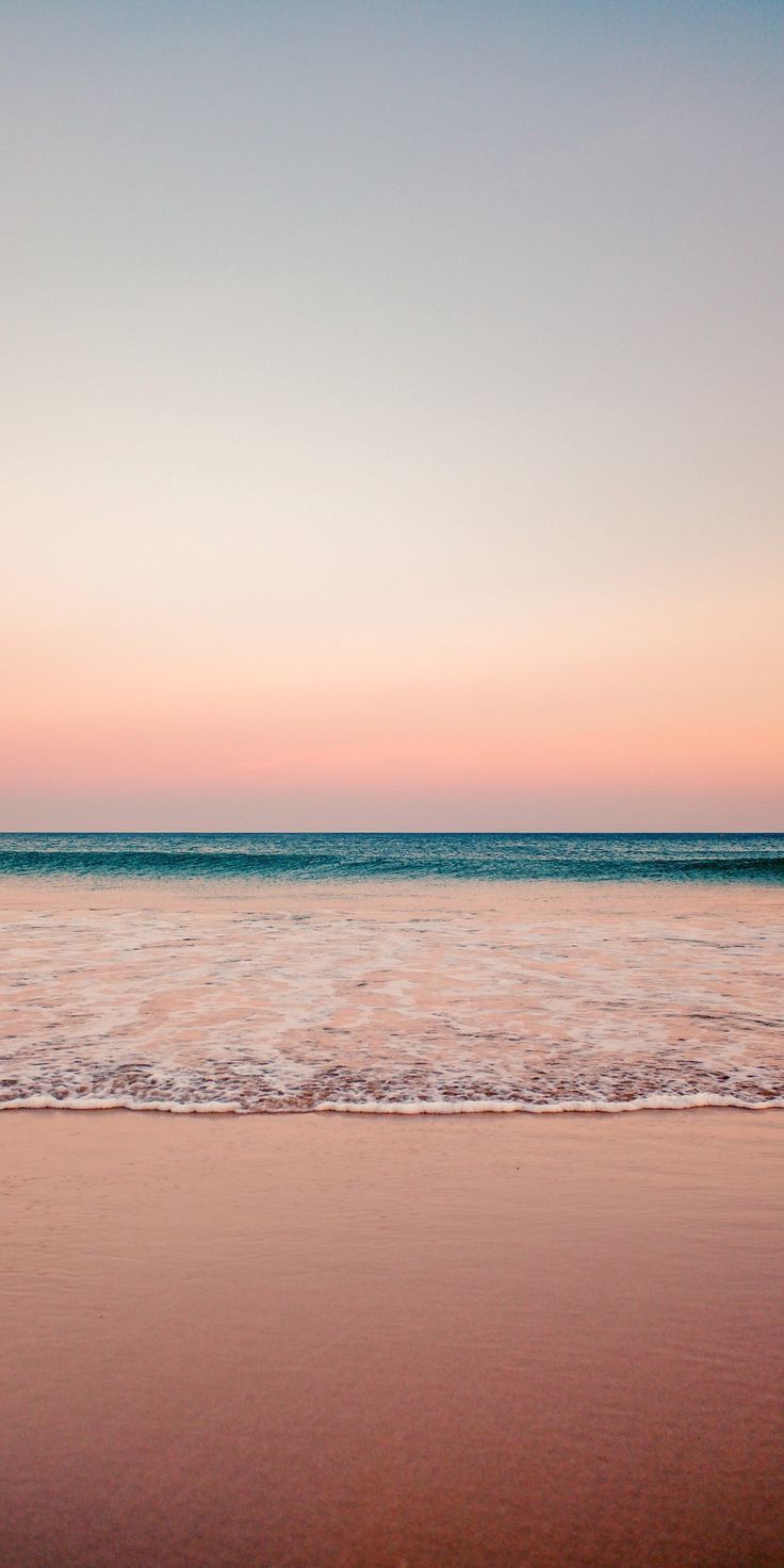 two surfers walking on the beach at sunset