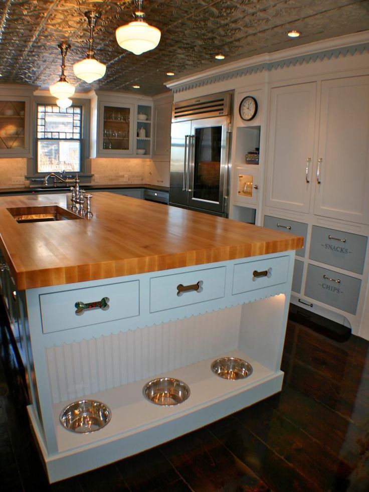 a large kitchen with an island and stainless steel appliances on the countertop, along with two dog bowls