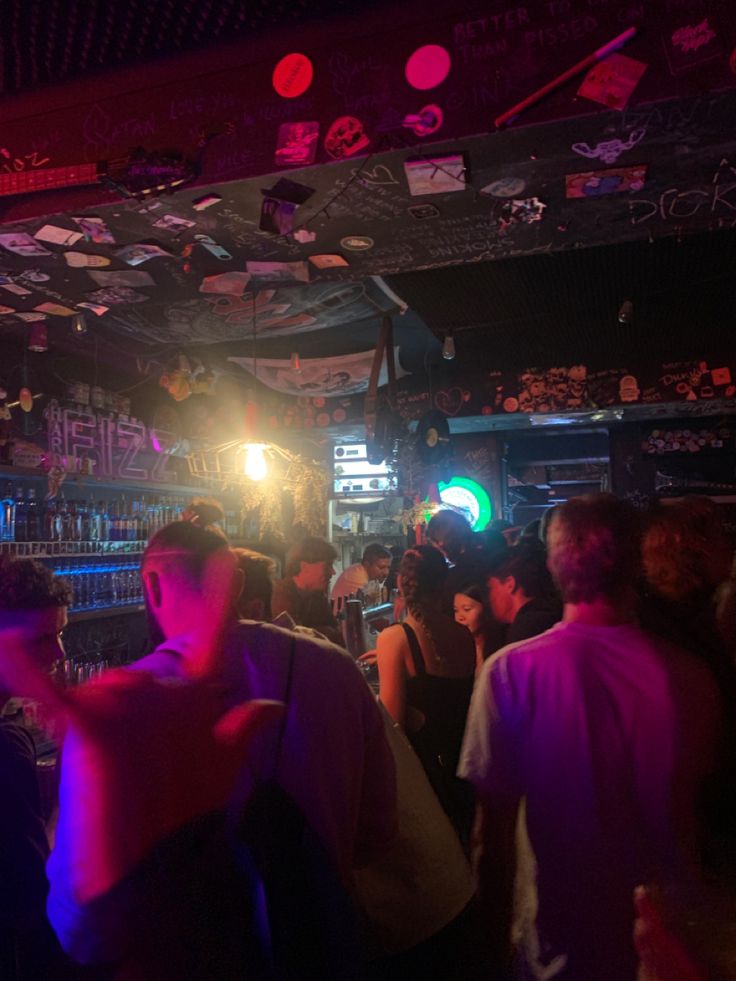 a group of people standing around in a room with purple lights on the ceiling and walls