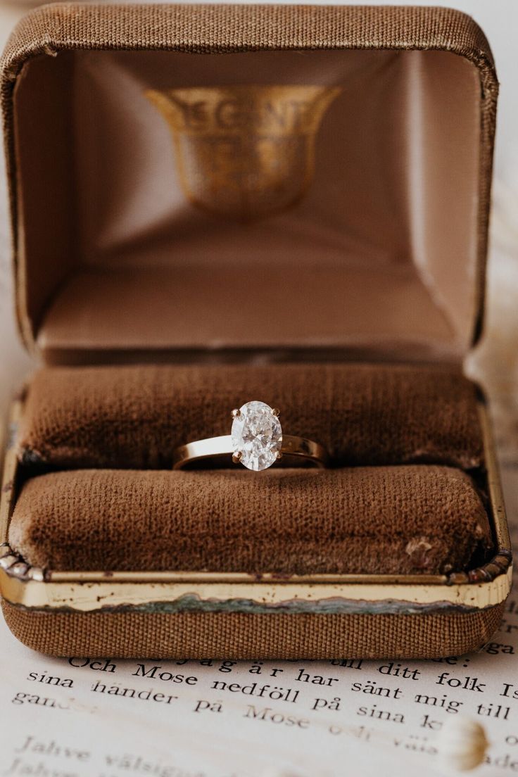 an engagement ring sitting in a box on top of a piece of paper