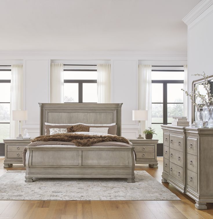 a large bedroom with white walls and wooden flooring, along with two lamps on either side of the bed