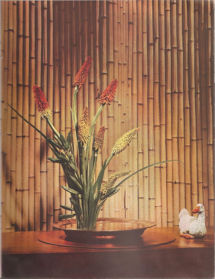 a painting of flowers in a vase on a table next to a duck and bamboo wall