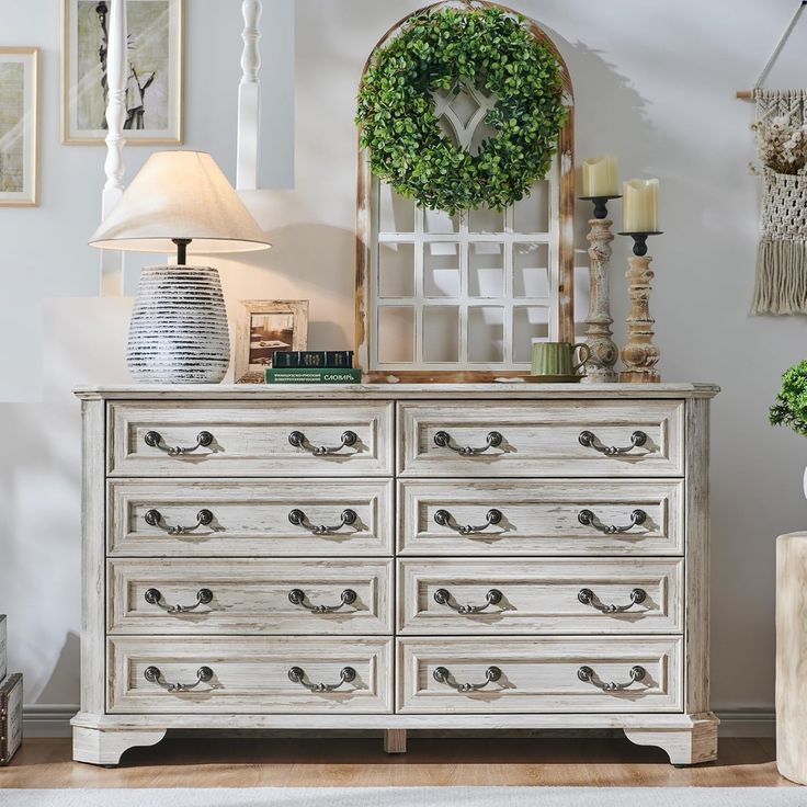 a white dresser sitting in a room next to a lamp