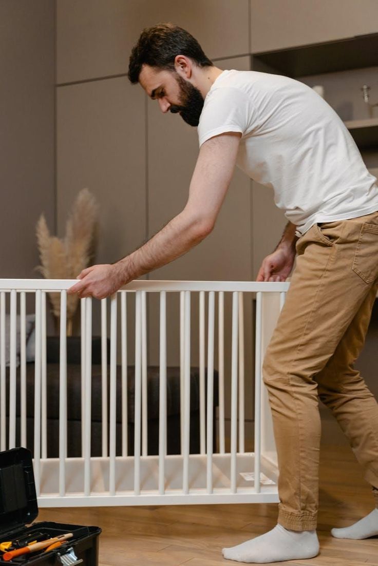 a man standing in front of a white crib