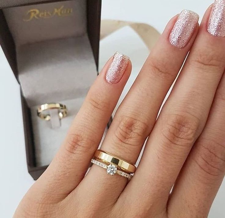 a close up of a person's hand with two rings and a ring box