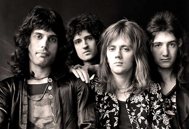 an old black and white photo of four young men with long hair posing for the camera