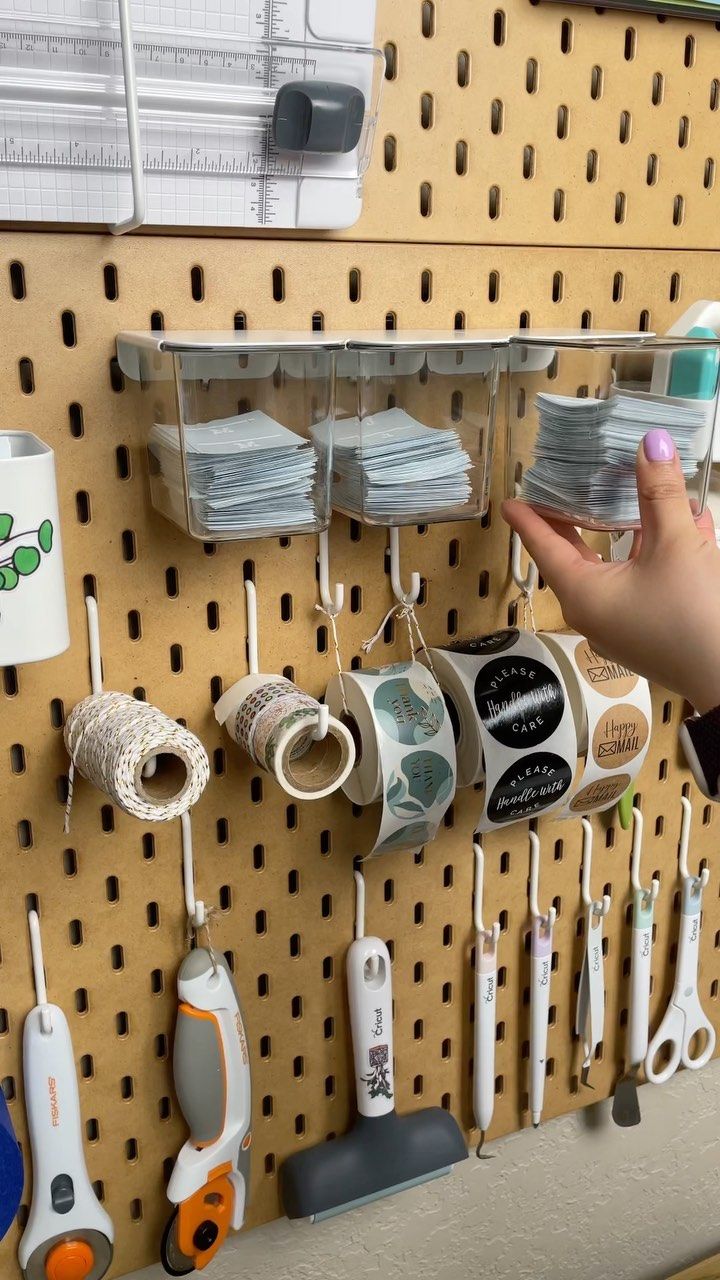 a person is holding up some cups and toothbrushes on a pegboard in a store