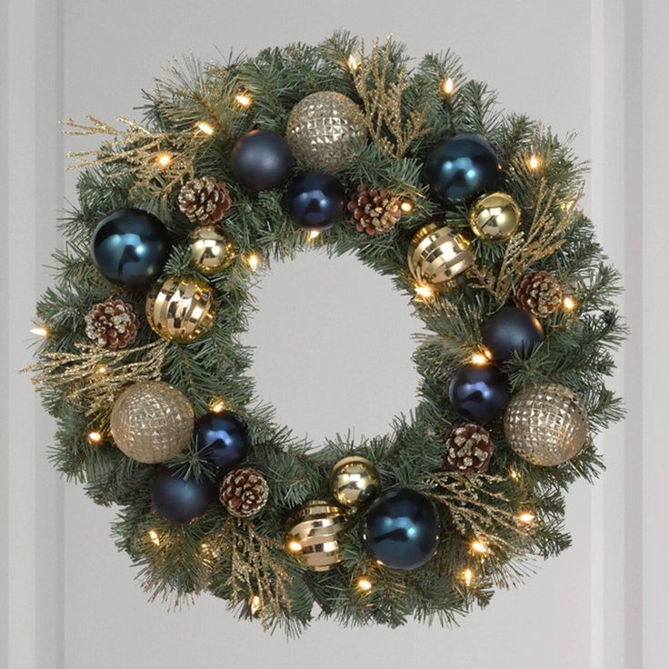 a christmas wreath with ornaments hanging from it's sides and lights on the front door