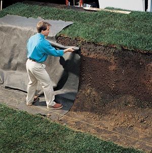 a man in blue shirt and khaki pants standing next to a large mound of dirt