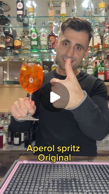 a man holding up a wine glass in front of a bar filled with liquor bottles