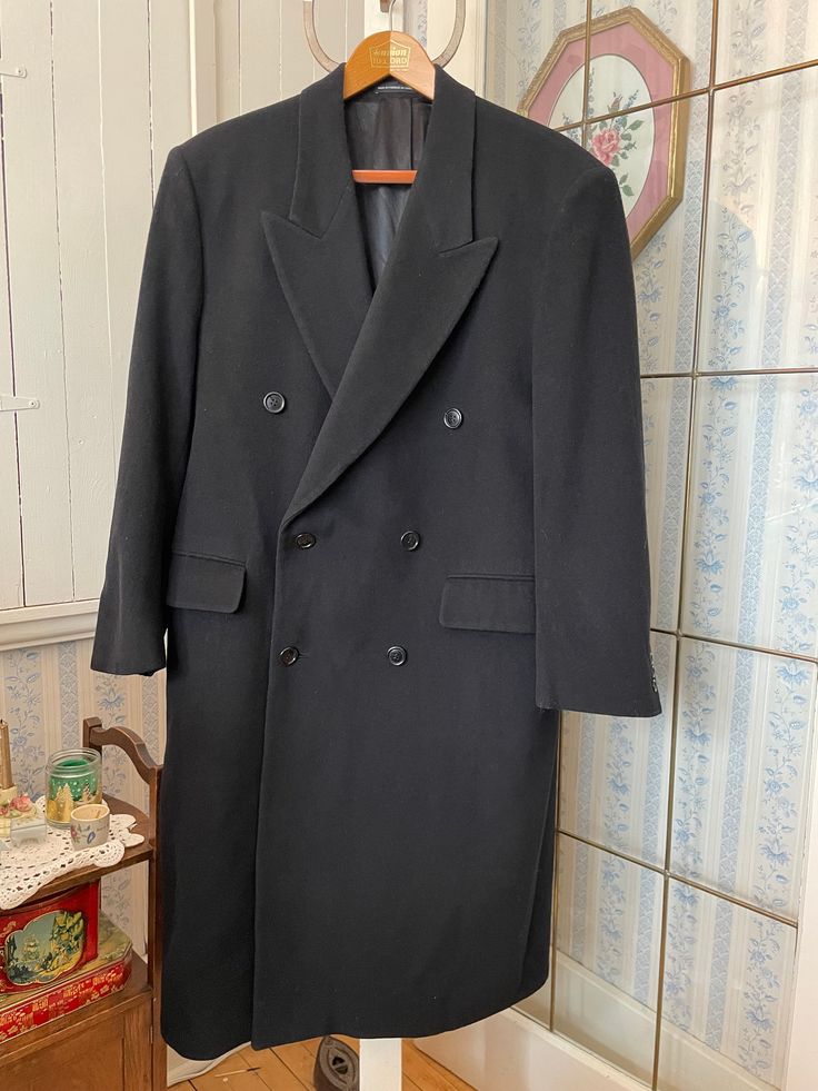 This handsome coat from Moore's is made from 70 per cent wool and 30 per cent polyester in classic navy blue. It has the original buttons on the front and cuffs, two outer pockets and one inner pocket, and is fully lined with dark blue silky lining. Marked size 40 short. The measurements, taken with the coat lying flat, are: shoulder to shoulder, 19 inches; armpit to armpit, 22 inches; sleeves, 24 inches; length, 47  inches; bottom edge, 38 inches. In very good condition. Formal Solid Color Long Wool Coat, Classic Black Long Pea Coat, Classic Long Black Pea Coat, Classic Long Pea Coat For Formal Occasions, Classic Long Pea Coat With Button Closure, Classic Long Solid Pea Coat, Classic Long Single Breasted Pea Coat, Classic Long Pea Coat, Classic Long Fitted Pea Coat