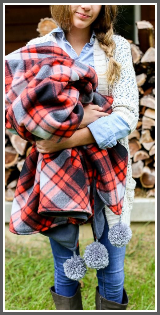 a woman holding a baby wrapped in a plaid blanket