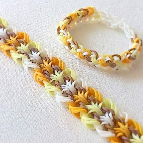 two bracelets made out of multicolored yarn sitting on top of a white surface