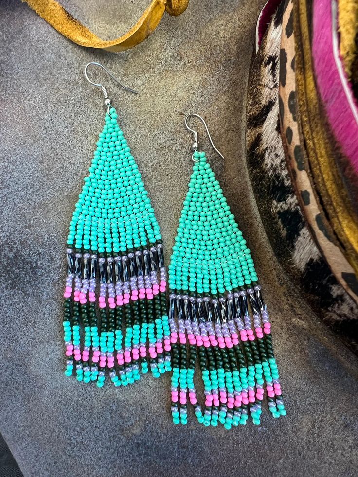 This item is available for local pick up from Magnolia, TX or select a shipping option and have it shipped directly to you. Spend over $99 and shipping is on me! Experience perfection with these charming seed bead earrings! They feature a delightful combination of turquoise, pink, black, and purple colors, adding a touch of vibrancy to your ensemble. Turquoise Beaded Earrings With Black Beads As Gift, Turquoise Earrings With Black Round Beads, Turquoise Beaded Earrings With Dangling Beads For Festivals, Turquoise Beaded Earrings For Festivals, Turquoise Earrings With Tiny Beads For Festivals, Festival Turquoise Beaded Earrings With Colorful Beads, Turquoise Earrings With Colorful Beads For Festival, Festival Turquoise Earrings With Tiny Beads, Festival Turquoise Earrings With Colorful Beads