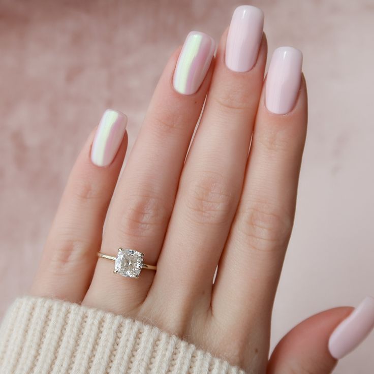 a woman's hand with pink and white manicured nails holding a diamond ring