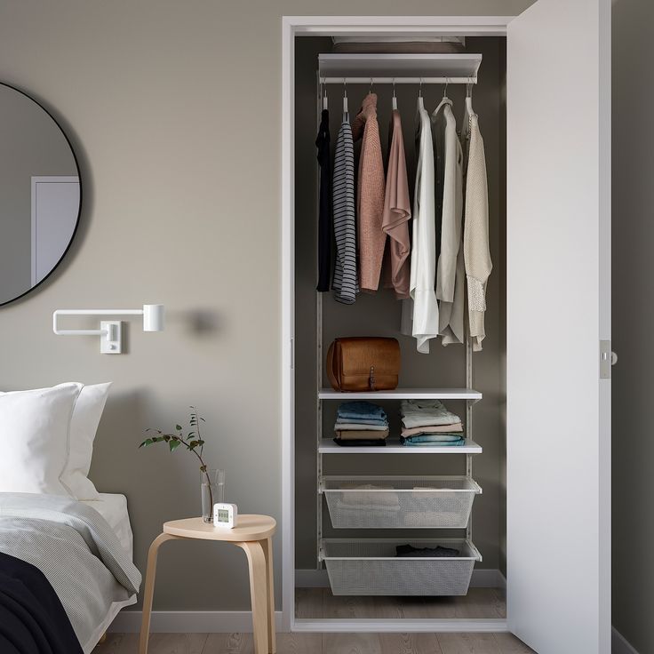 an open closet with clothes on hangers and a mirror in the corner next to it