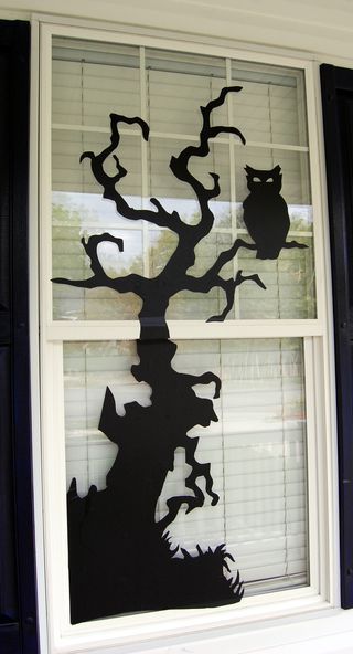 an owl and tree cut out of paper on a window sill