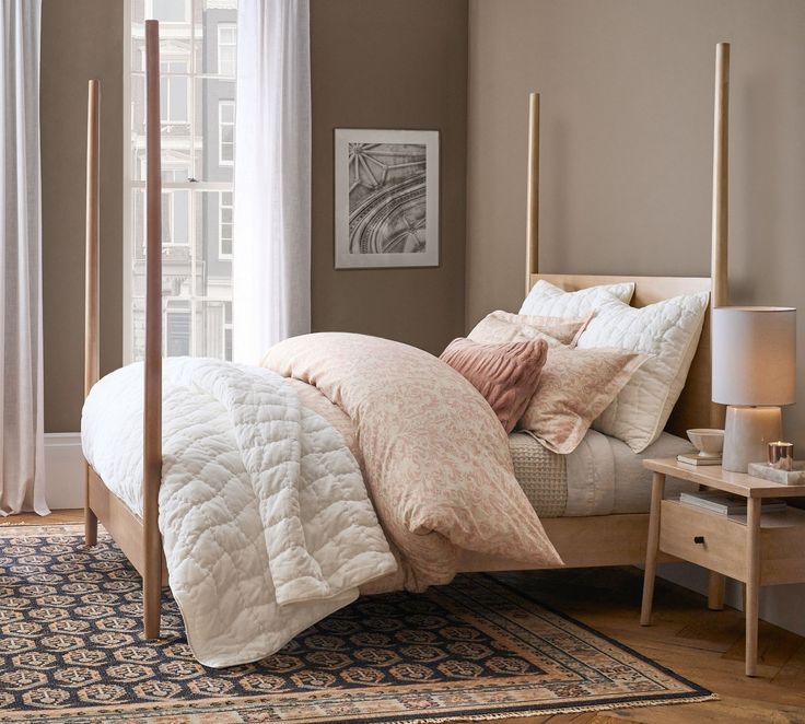 a bed in a bedroom with beige walls and white curtains