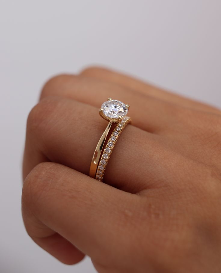 a woman's hand holding a gold ring with a diamond on top and side stones around the band