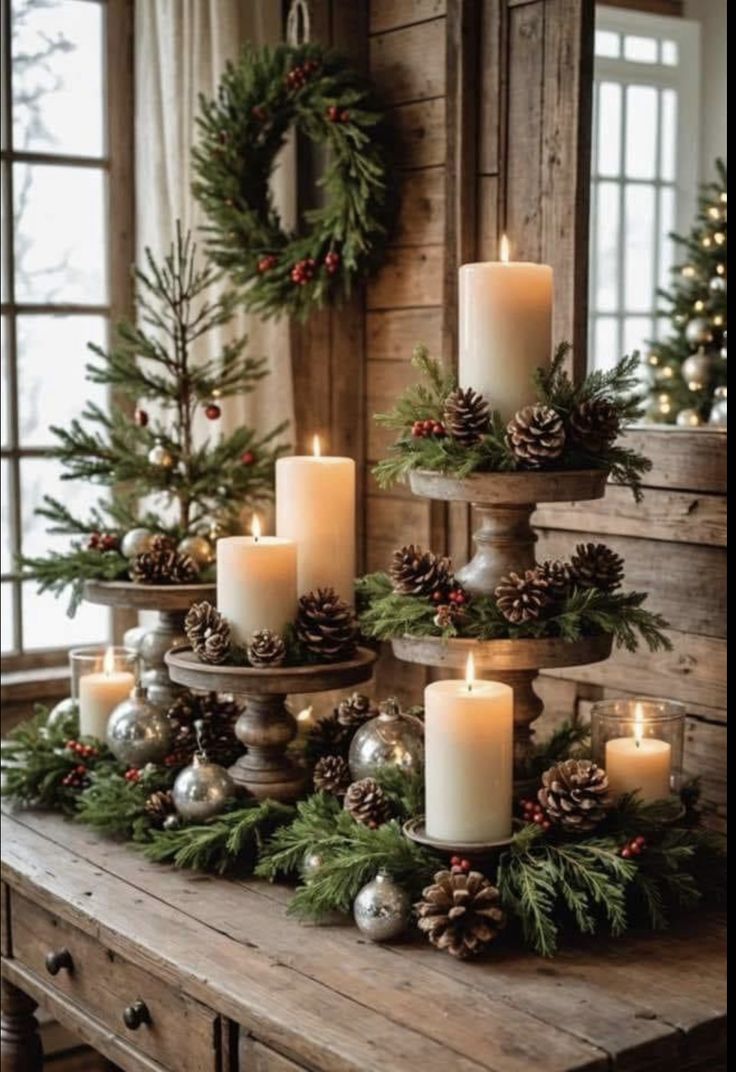 christmas candles are arranged on a table with pine cones and evergreen branches in the center