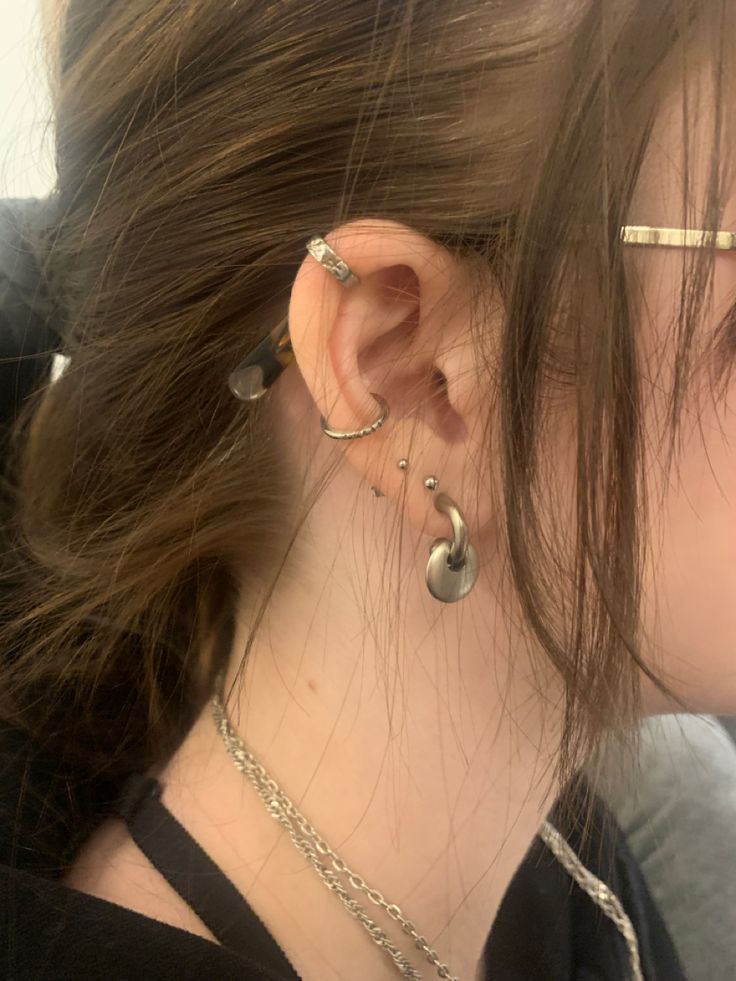 a close up of a person with ear piercings on their ears and wearing metal chains