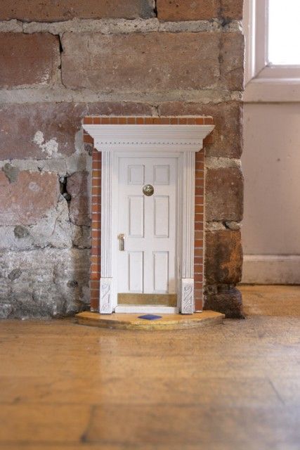 an open door in the middle of a room with brick walls and wood flooring