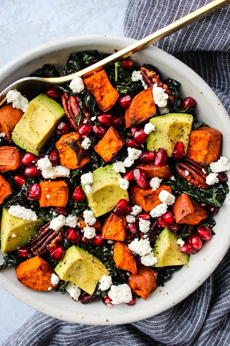 a white bowl filled with sweet potatoes, avocado and pomegranate