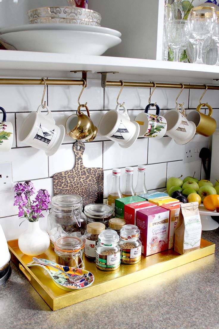 the kitchen counter is covered with cups and saucers, fruit, and other items