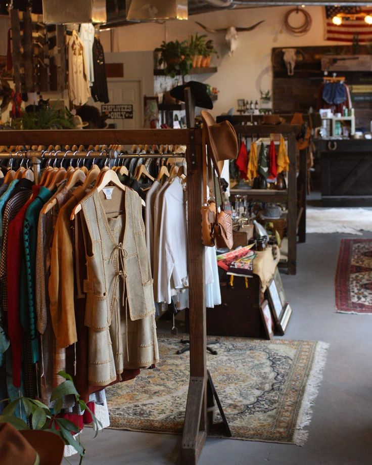 a clothing store with clothes hanging on racks and rugs in the foreground,