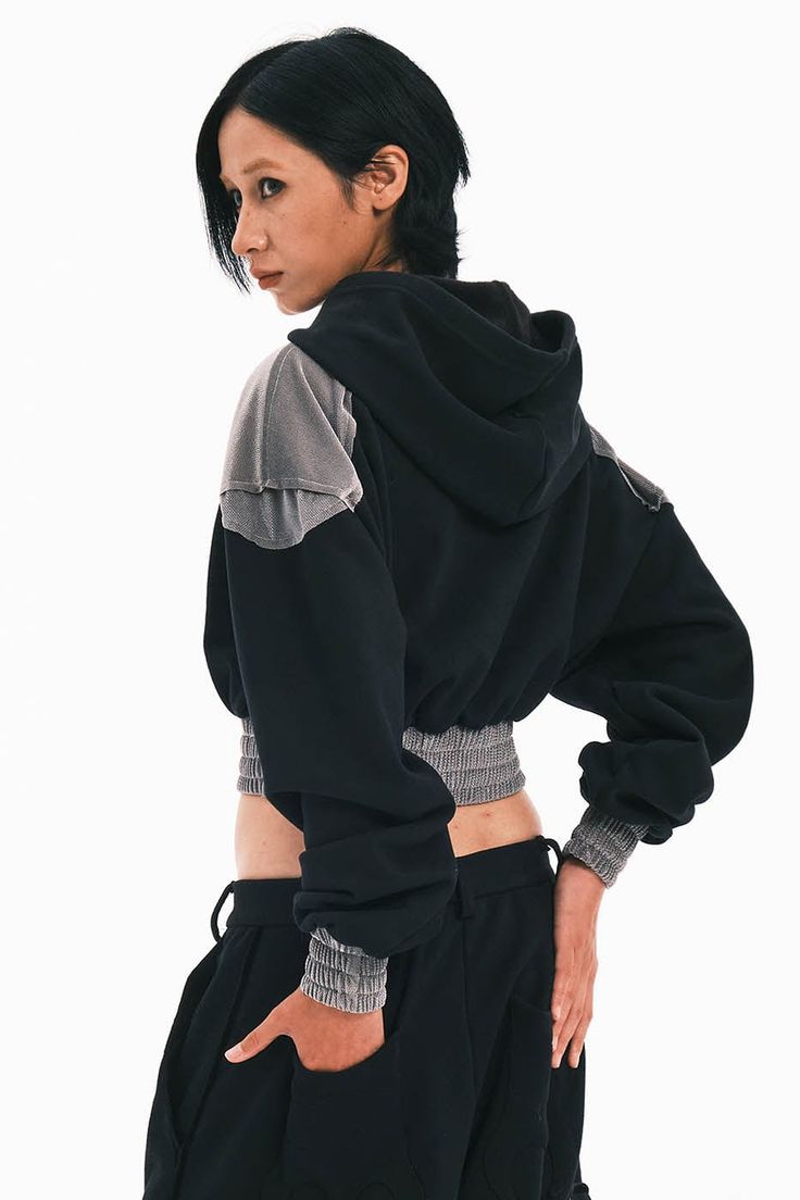 The Bat Patchwork Cropped Hoodie stands at the intersection of casual comfort and avant-garde style. This piece features a distinctive patchwork design on the front that resembles a bat, setting a bold and playful tone. Central to the hoodie is the brand's logo, anchoring the design with a sense of identity. The shoulders are enhanced with fabric that mimics the look of armor plating, adding an edge of sophistication and strength to the overall silhouette. The hoodie is designed with tightened h Hooded Jacket With Contrast Color For Streetwear, Contrast Color Hooded Jacket For Streetwear, Contrast Color Hoodie For Fall Streetwear, Contrast Color Hoodie For Streetwear In Fall, Trendy Black Hoodie With Patchwork, Winter Hooded Jacket With Contrast Color For Streetwear, Black Hoodie With Contrast Color For Streetwear, Long Sleeve Patchwork Sweatshirt In Athleisure Style, Long Sleeve Hooded Jacket With Patchwork For Streetwear