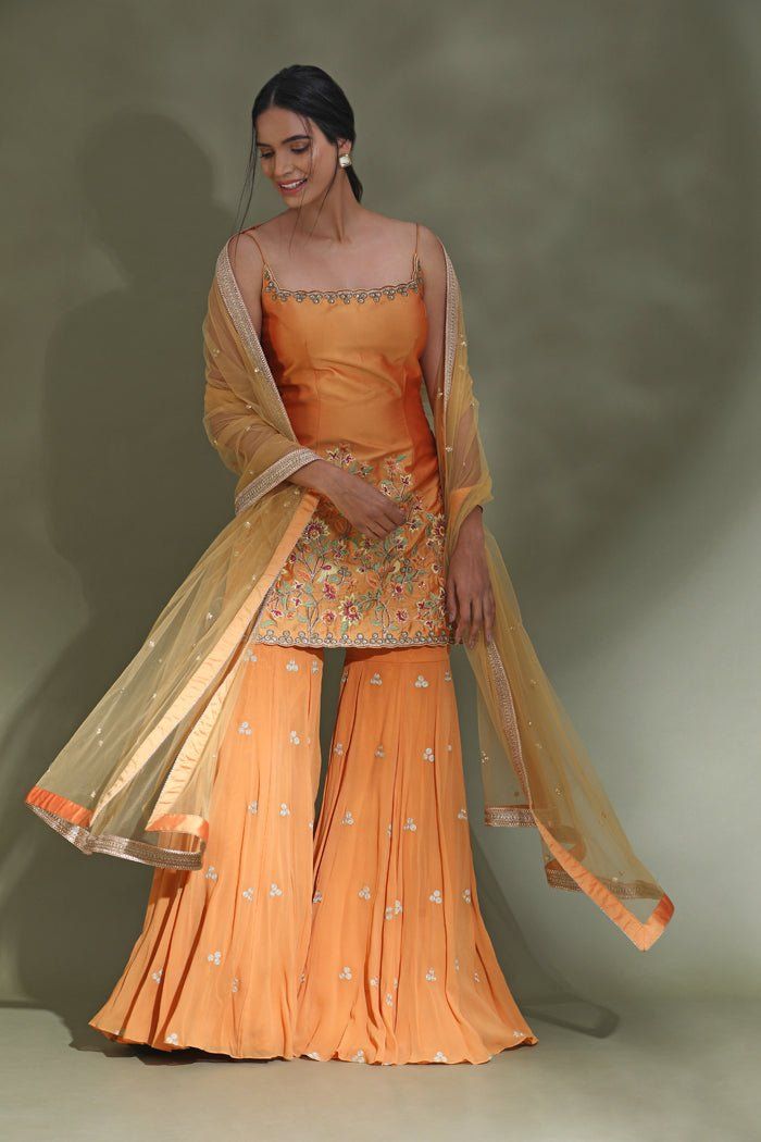 Shop beautiful orange embroidered sharara suit online in USA with dupatta. Look your best at weddings and parties in Indian dresses, designer lehengas, Anarkali suits, designer gowns, salwar suits, sharara suits from Pure Elegance Indian fashion store in USA.-full view