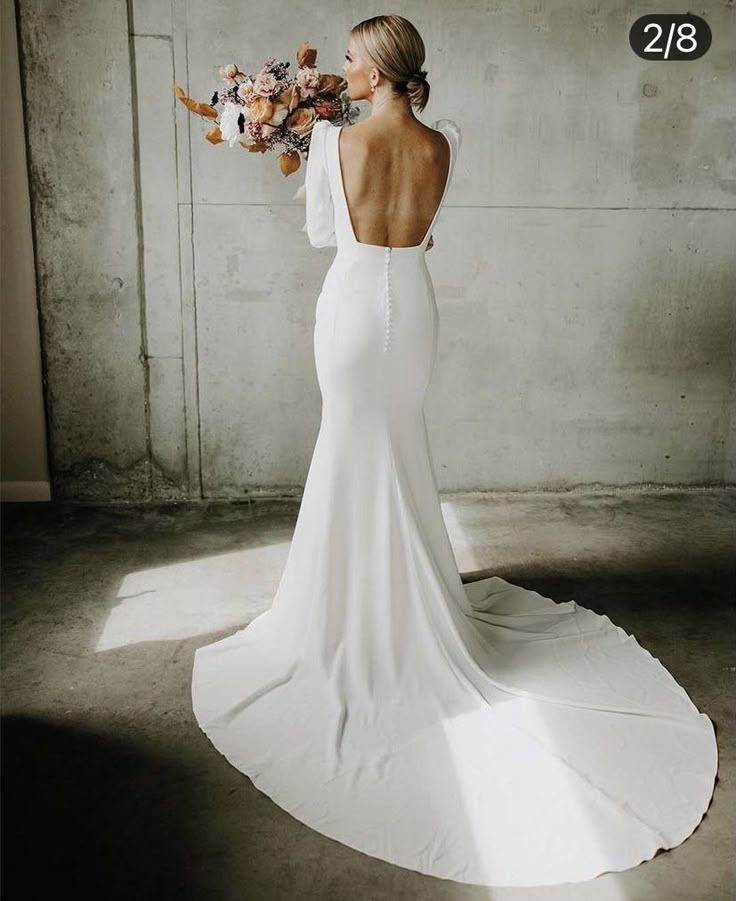 a woman in a white dress holding flowers and looking at the back of her dress