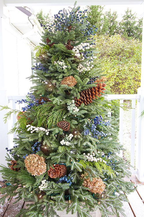 a christmas tree decorated with pine cones and blue berries