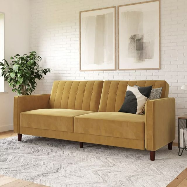 a living room with a couch, rug and two paintings on the wall behind it